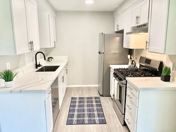 A kitchen with white cabinets and a stainless steel refrigerator